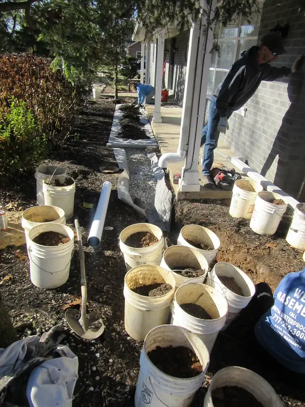 Drainage materials staged beside a foundation