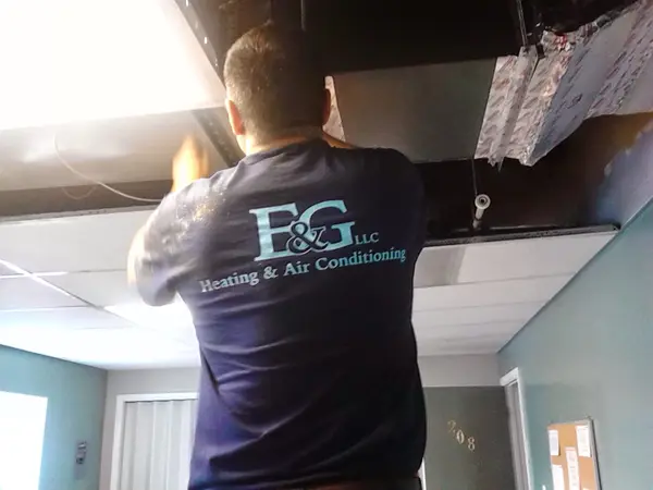 Technician working around HVAC ductwork