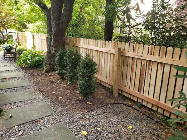 Wood fence installed around established garden landscaping