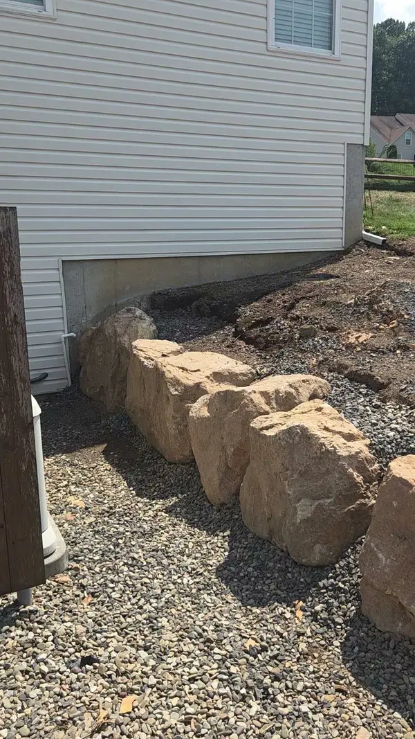 Boulders arranged beside a foundation planting area