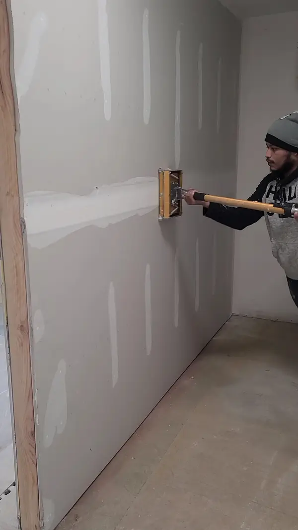 Worker preparing drywall surfaces