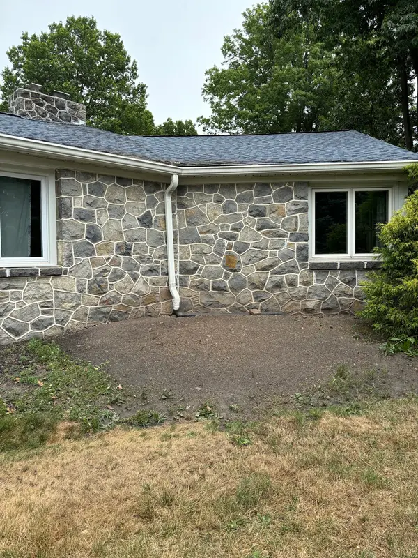 Cleared planting bed beside a stone house