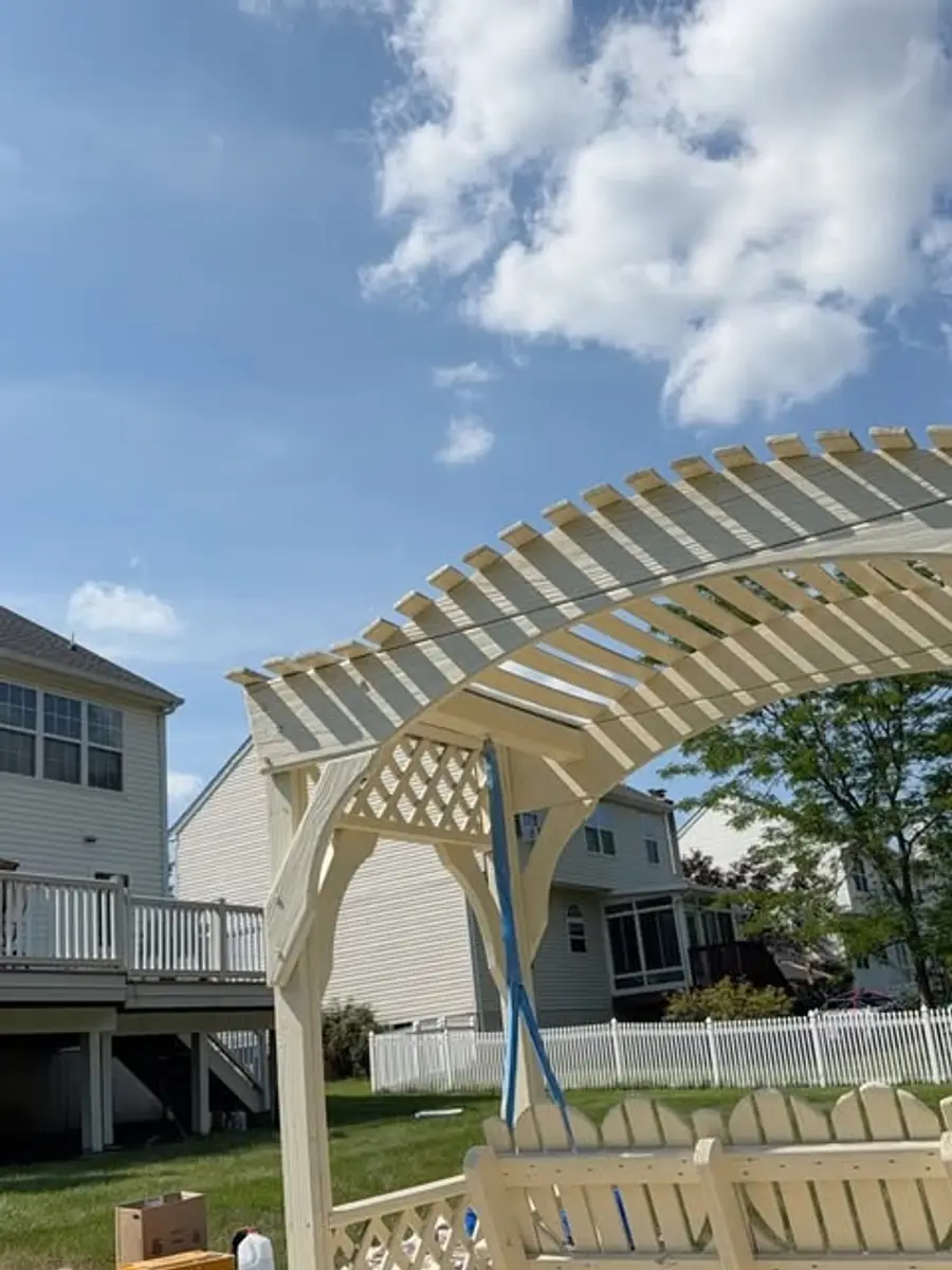Freshly sprayed cream wooden pergola and outdoor bench in a residential backyard