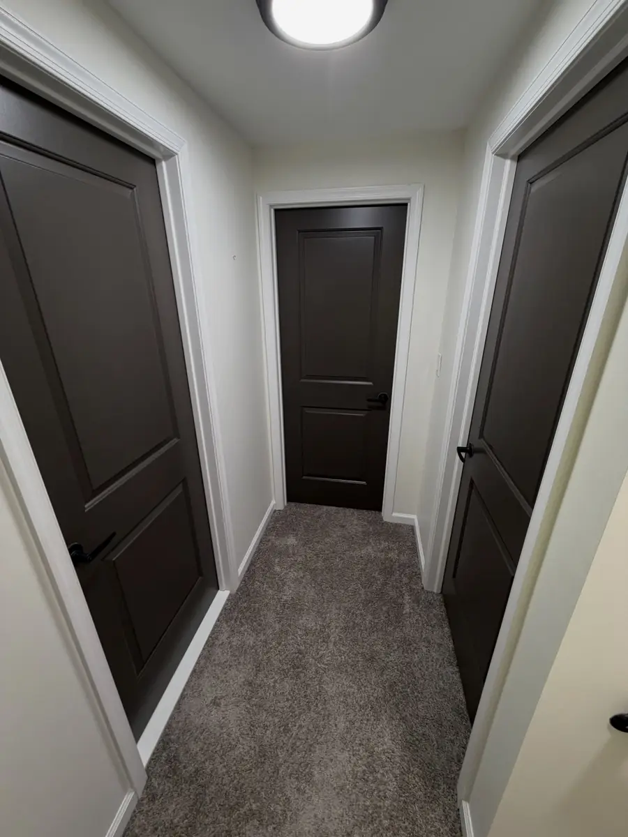 Hallway with off-white walls and dark bronze paneled interior doors with white casing