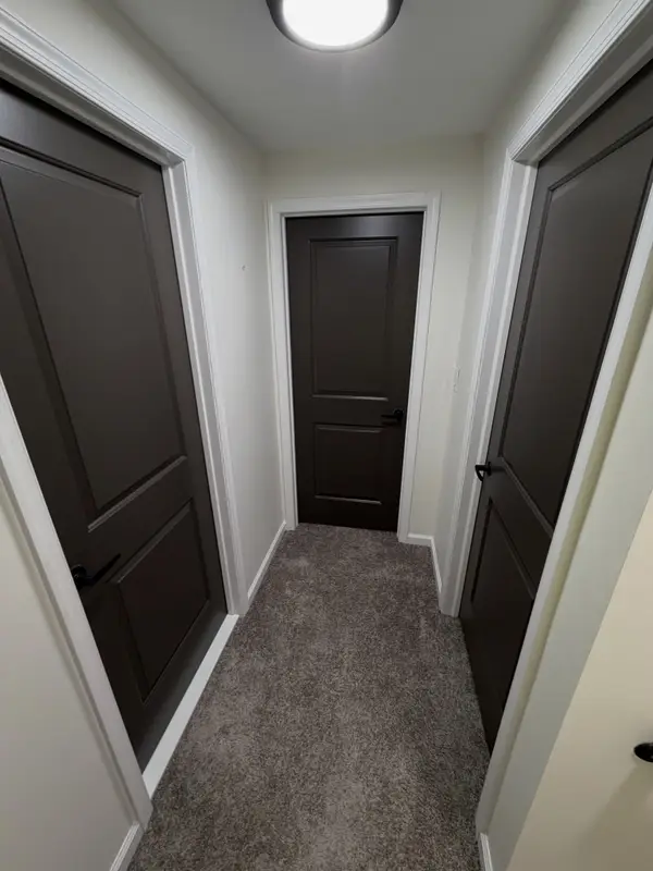Hallway with off-white walls and dark bronze paneled interior doors with white casing