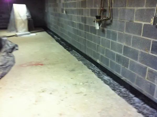 Interior perimeter drainage channel beside a block wall