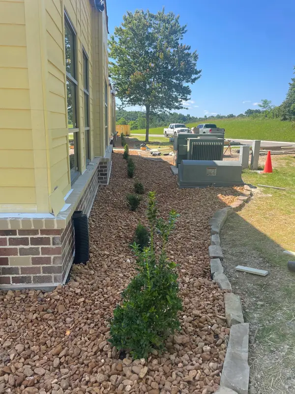 Stone-covered planting bed beside a house