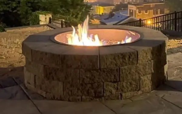 Round stone fire pit on a backyard patio by Ashenfelter Bros Masonry