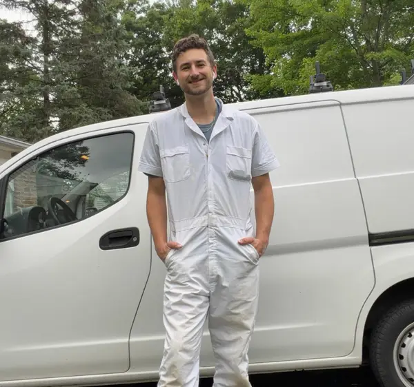 Stephen Gartner in white painter coveralls standing beside a white work van