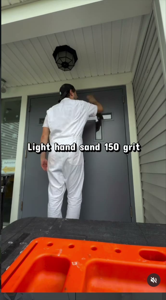 Stephen hand-sanding a gray exterior door before paint